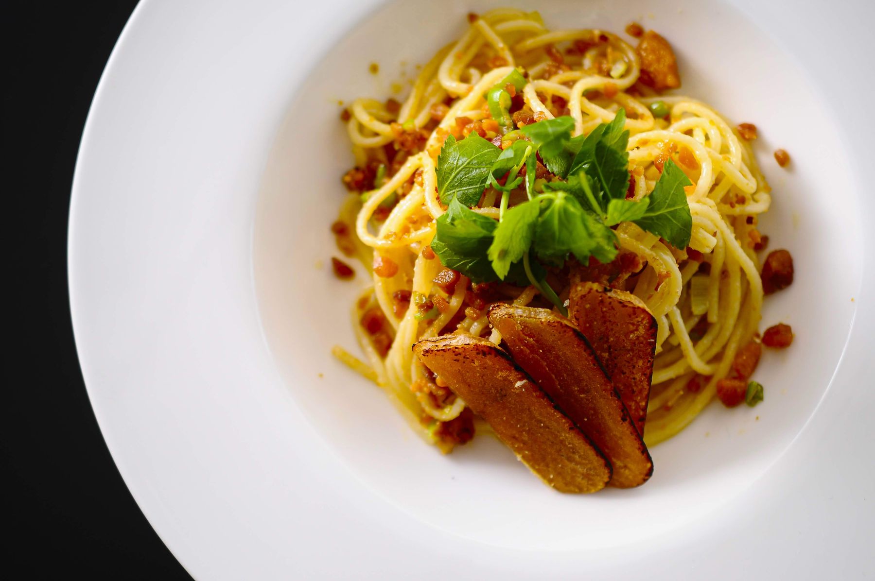 パスタに、焼き目をつけたからすみの薄切りと刻んだからすみをのせた皿