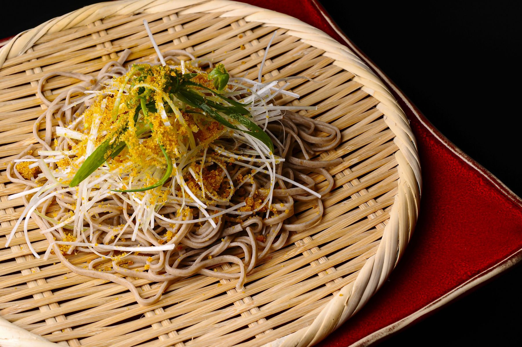 ざる蕎麦に白髪ねぎとからすみパウダーをのせた皿